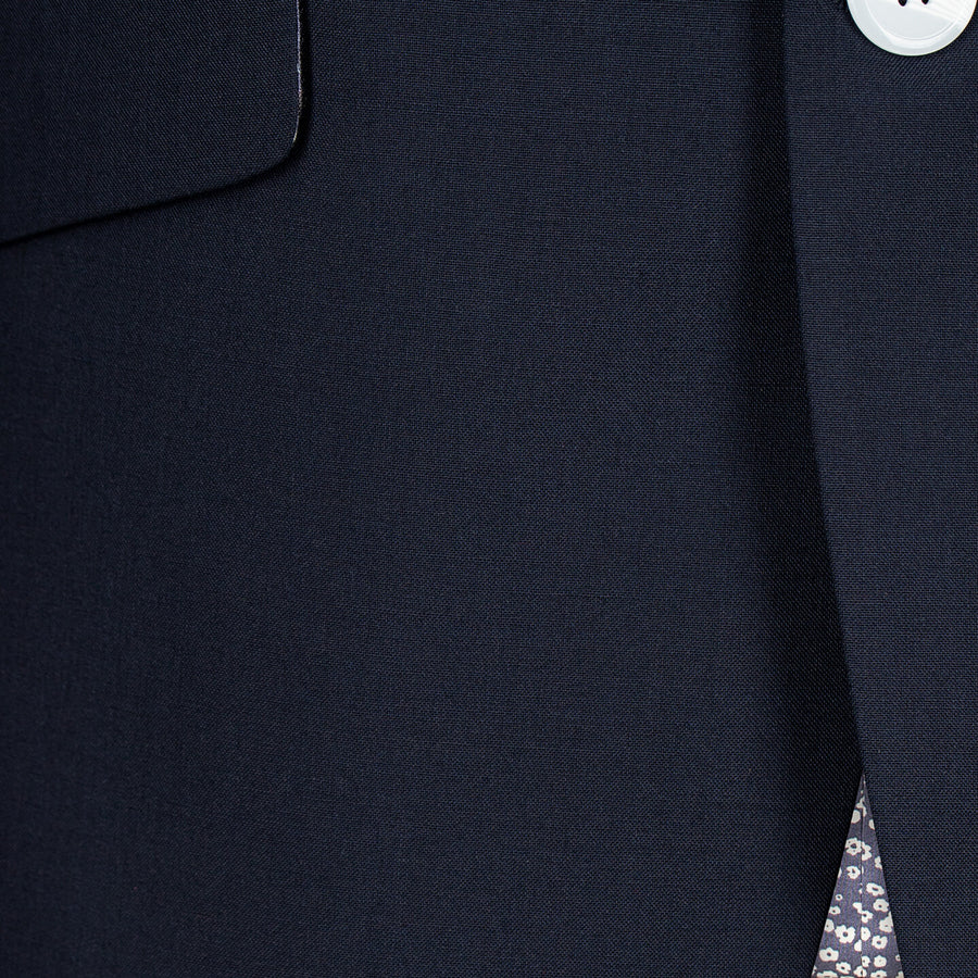 Close-up of a navy blue suit jacket with a button and pocket detail.