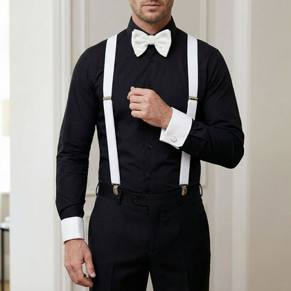 Man wearing a black suit with white suspenders and bow tie against a neutral background