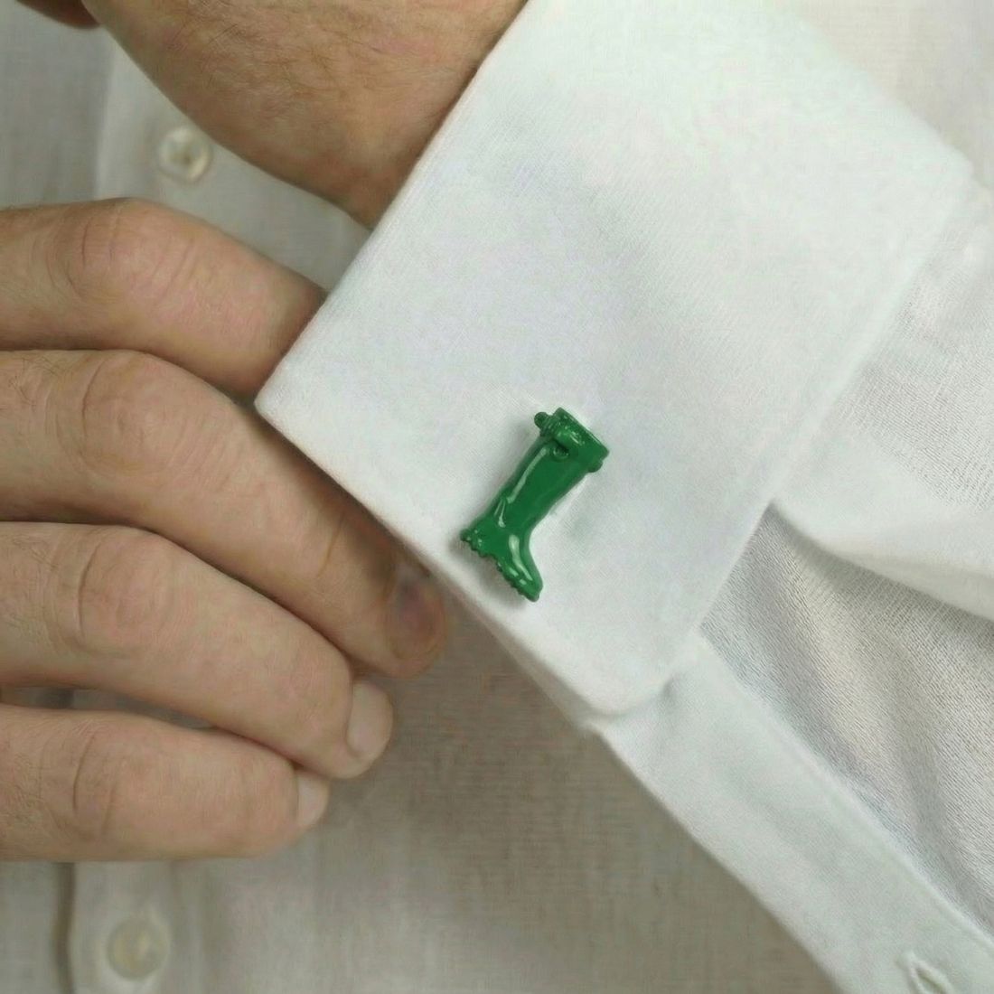 Green cufflink on a white shirt cuff. Bown of London