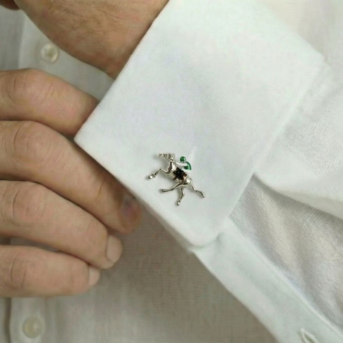 Cufflink on a white shirt cuff with a hand adjusting it. Bown of London