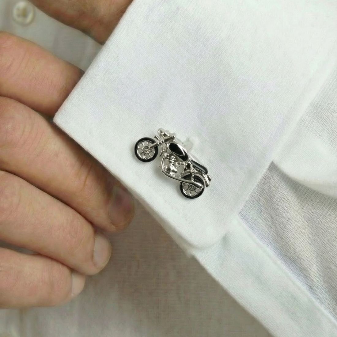 Motorcycle-shaped cufflink on a white shirt with a hand adjusting it. Bown of London