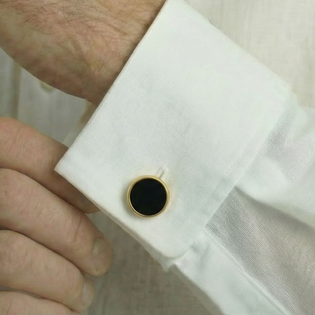 Close-up of a cufflink on a white shirt sleeve. Bown of London