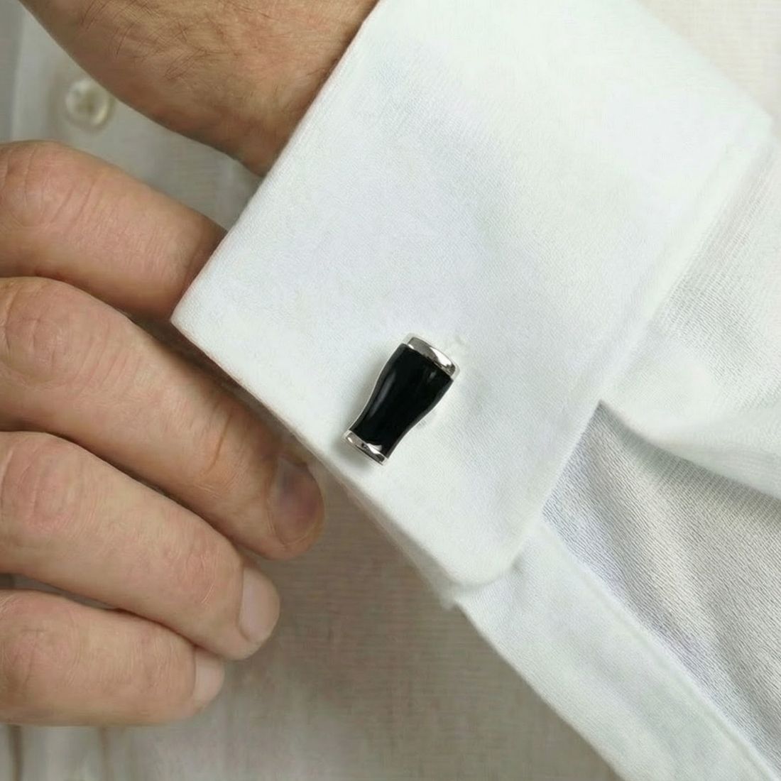 Cufflink being adjusted on a white shirt cuff. Bown of London