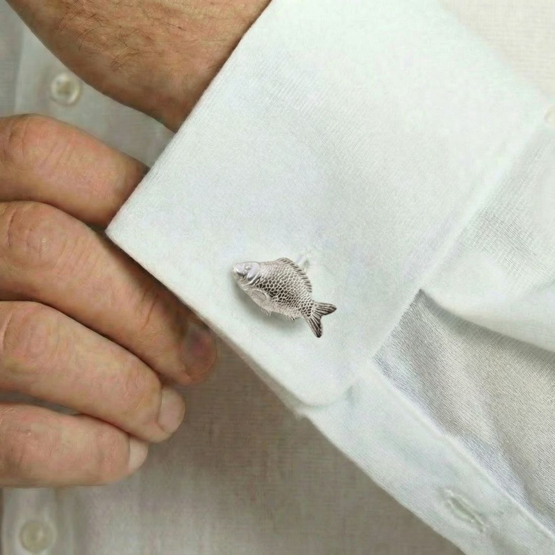 Fish-shaped cufflink on a white shirt cuff