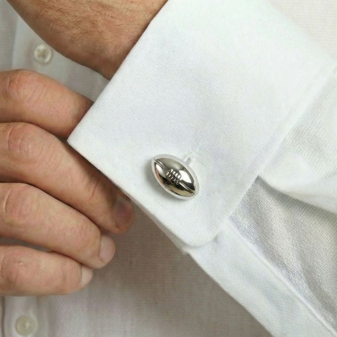 Close-up of a white shirt cuff with a button being adjusted.