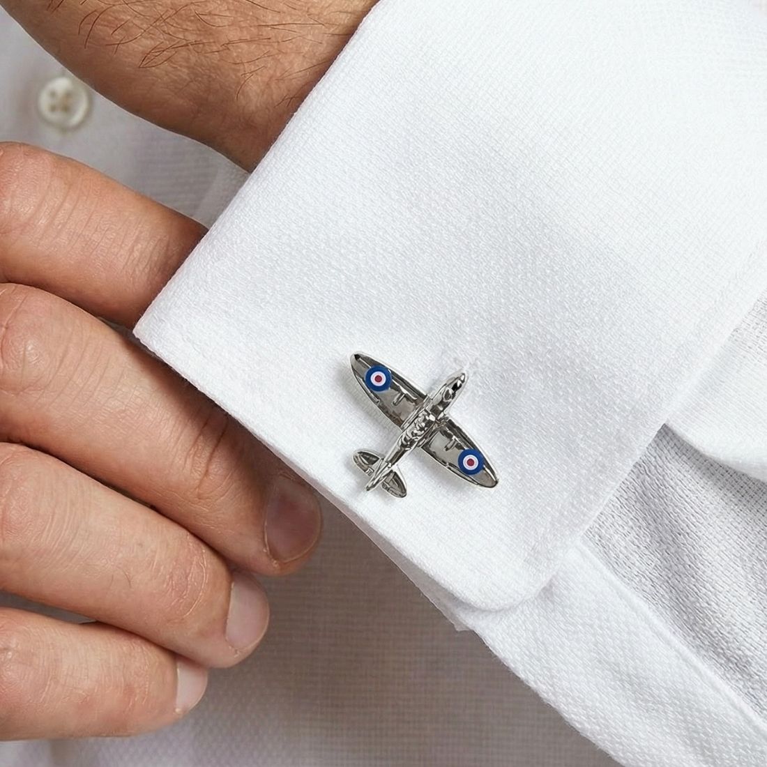 Cufflink shaped like a small airplane on a white shirt cuff. Bown of London