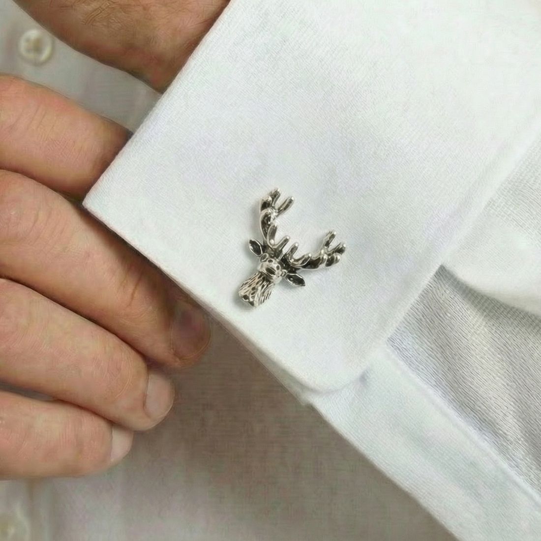 Silver deer-shaped cufflink on a white shirt cuff. Bown of London