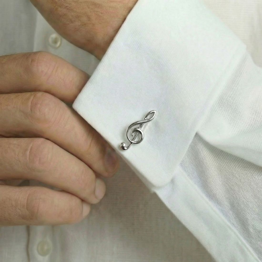 Silver treble clef cufflink on a white shirt. Bown of London