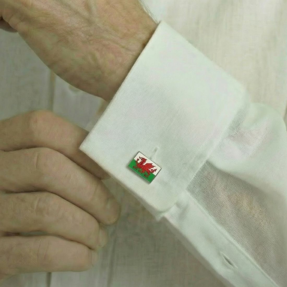Cufflink with a Welsh flag design on a white shirt cuff. Bown of London.