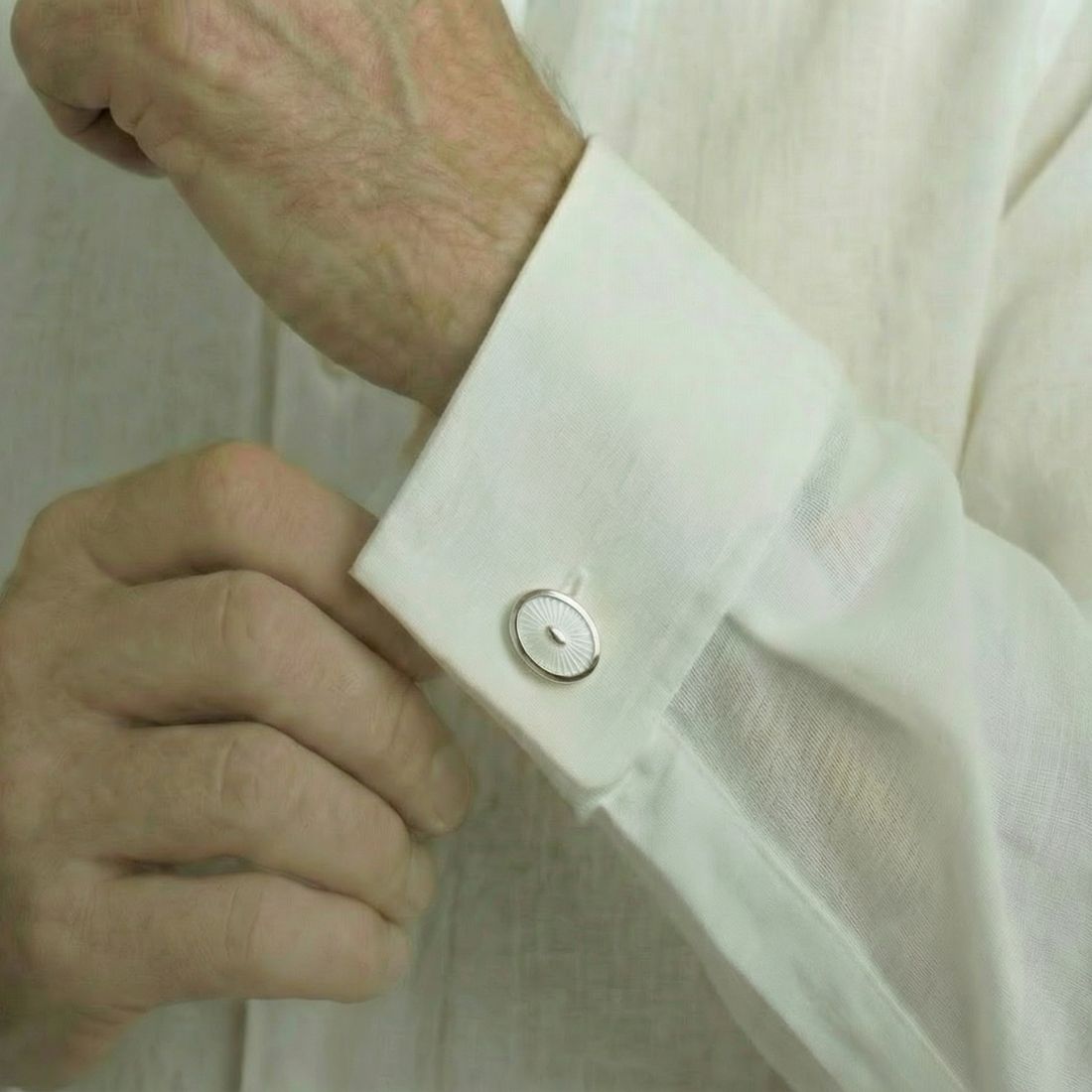 Close-up of a person adjusting the cuff of a white shirt. Bown of London.